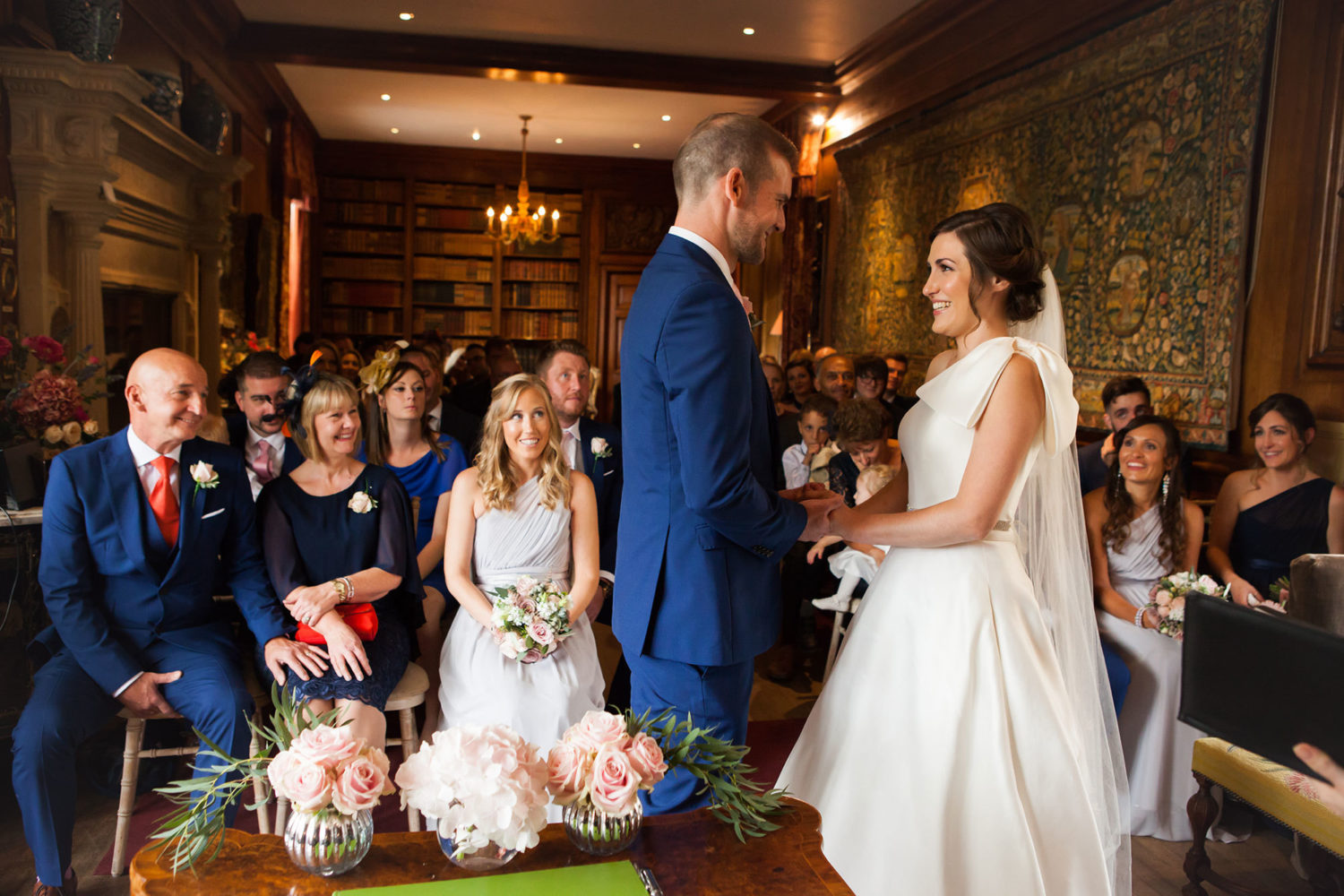 A couple face each other in front of seated guests