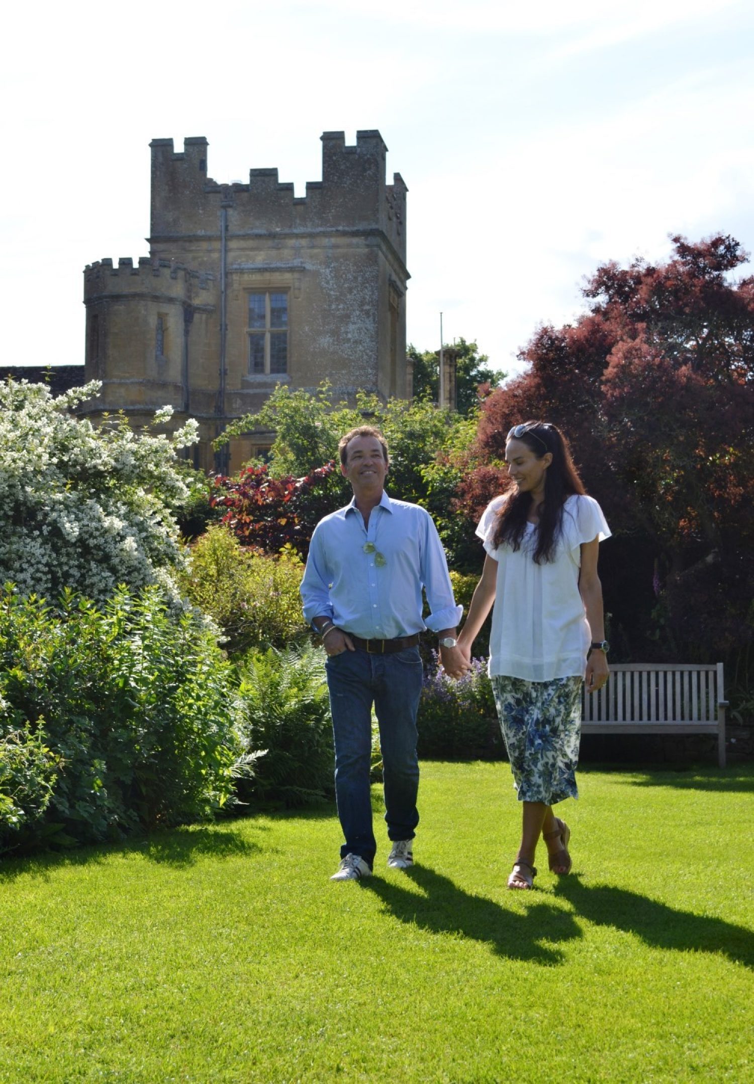 A smiling couple walk hand in hand in the Secret Garden