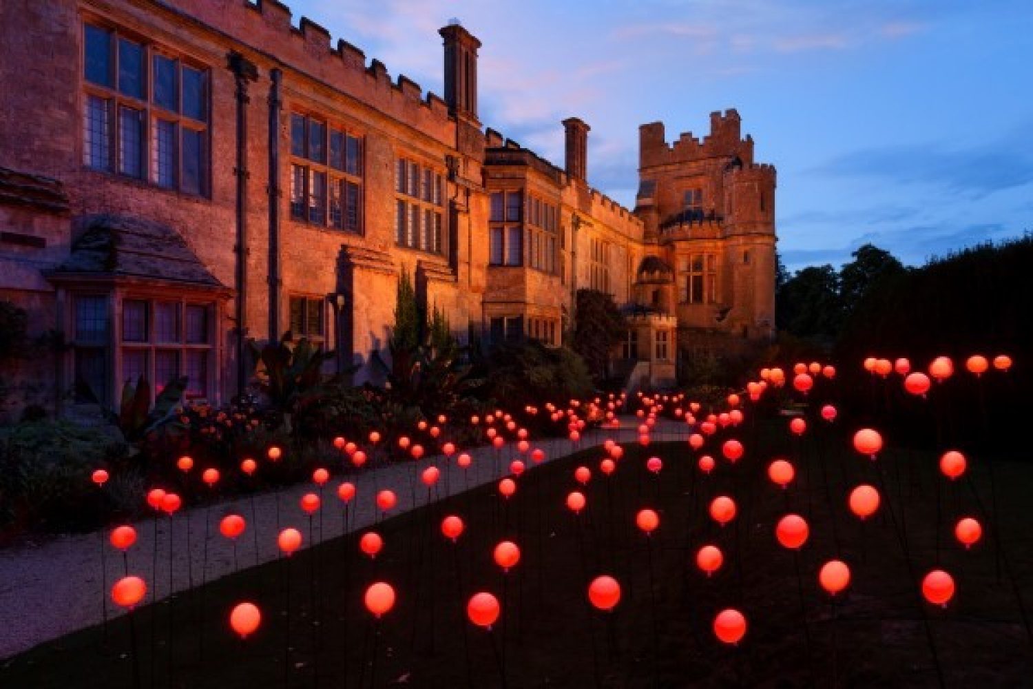 Dusk shot of field of illuminated poppies outside exterior of Sudeley Castle